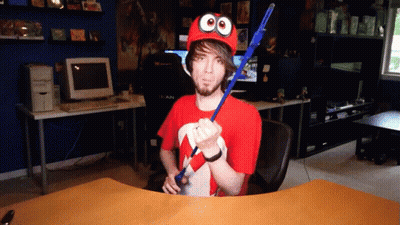 Man In Red Hat With Googly Eyes Holding Blue Stick GIF