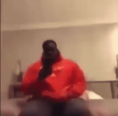 Man In Red Hoodie Talking On Phone On Bed GIF