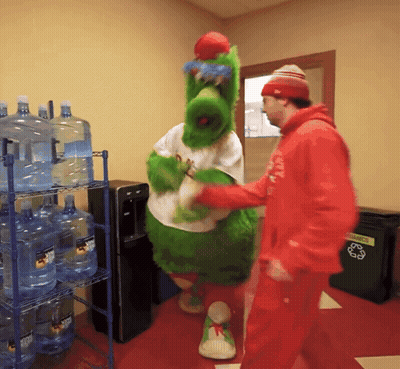 Man In Red Hoodie Talks To Green Mascot At Recycling Bin GIF