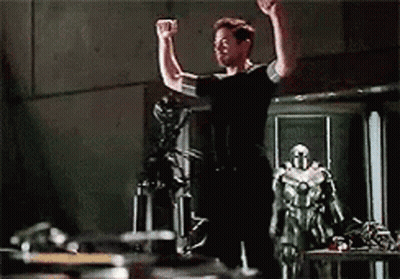 Man In Red Iron Man Suit Standing In Front Of Building GIF