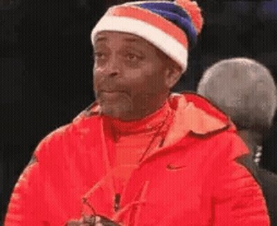 Man In Red Jacket And Blue-White Hat Looking GIF