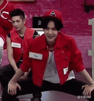 Man In Red Jacket And Hat Kneeling By Pink Wall GIF