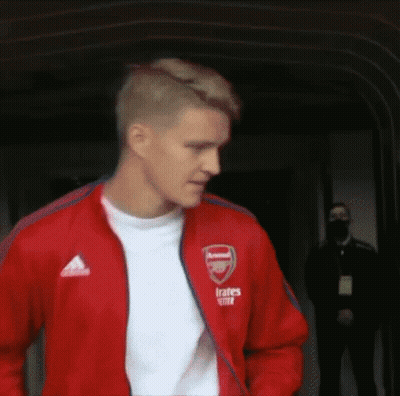 Man In Red Jacket And White Shirt Walking Down Hallway GIF