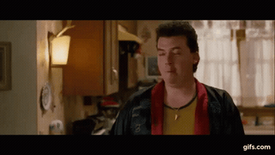 Man In Red Jacket And Yellow Shirt Eyes Closed In Kitchen GIF