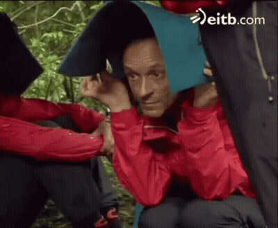 Man In Red Jacket Covering Head With Blue Blanket In Rain GIF