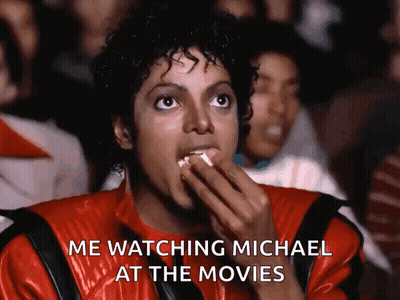 Man in Red Jacket Eating Popcorn Says Me Watching Michael at the Movies