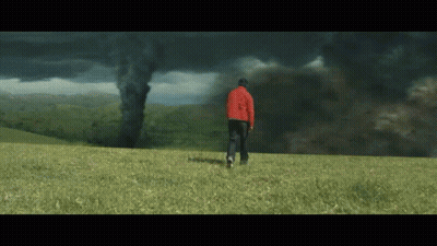 Man In Red Jacket Facing Tornado In Field GIF
