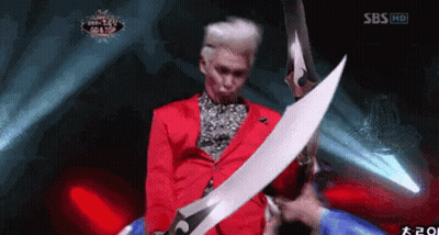 Man In Red Jacket Holding Large Sword In Front Of SBS Logo GIF