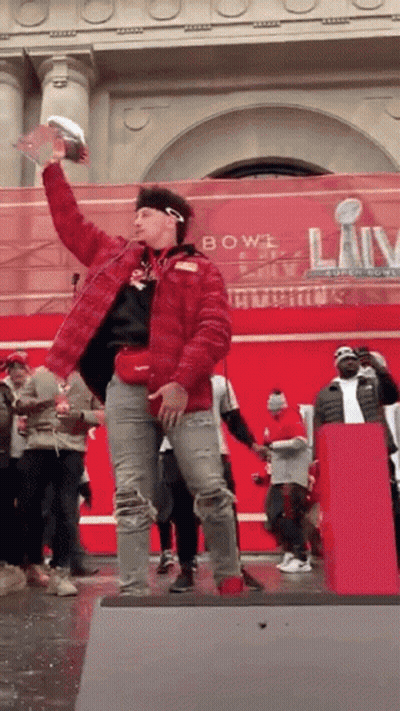 Man In Red Jacket Holding Trophy On Stage GIF