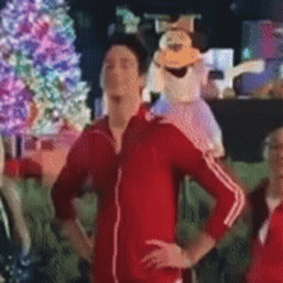 Man In Red Jacket In Front Of Christmas Tree GIF