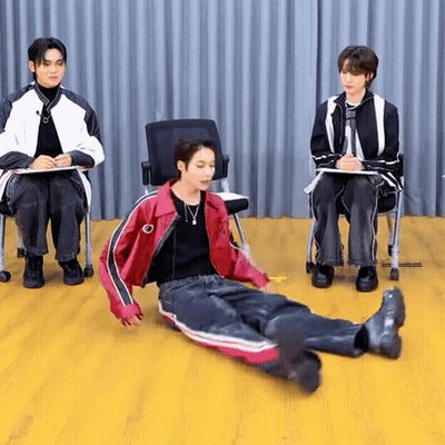 Man In Red Jacket Laying On Floor Two Men Behind GIF