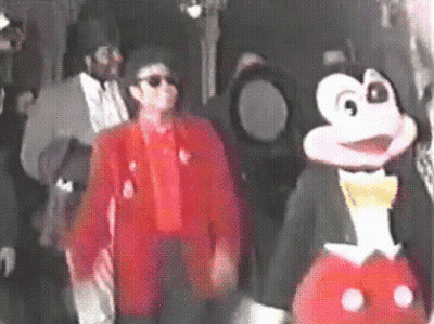 Man In Red Jacket Next To Mickey Mouse Costume GIF