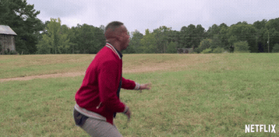 Man In Red Jacket Running Through Grassy Field With Netflix Logo GIF