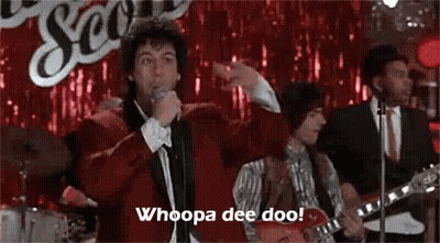 Man In Red Jacket Singing Into Microphone With Band GIF