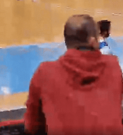 Man In Red Jacket Sitting Against Blue Wall GIF