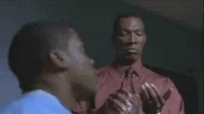 Man In Red Jacket Standing By Woman In Blue Shirt At Desk GIF