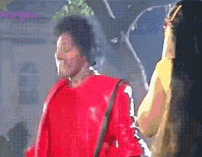 Man In Red Jacket Standing Next To Woman With Long Hair GIF