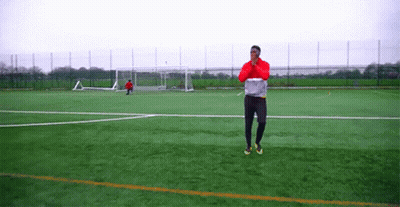 Man In Red Jacket Standing On Soccer Field With Goal GIF