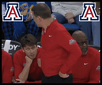 Man In Red Jacket Talking To Man In Blue And White Logo GIF