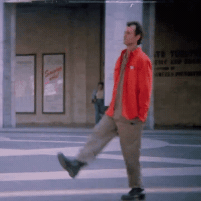 Man In Red Jacket Walking Down Street GIF