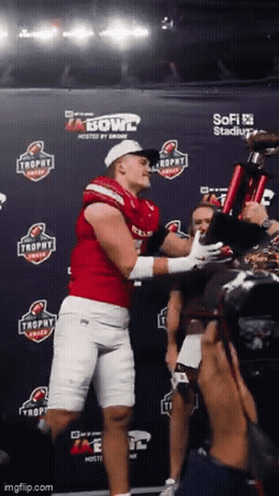 Man In Red Jersey Holding Trophy In Front Of Bowl Sign GIF