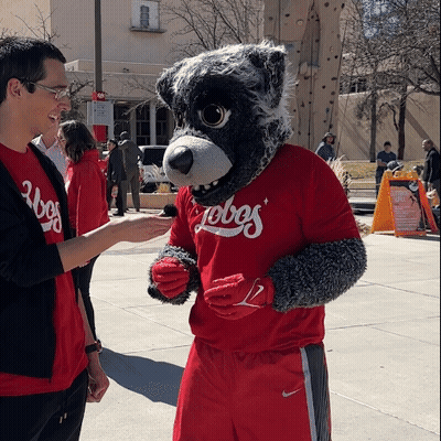 Man In Red Lobos Shirt Talks To Mascot GIF