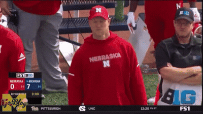 Man In Red Nebraska Shirt In Front Of Scoreboard GIF
