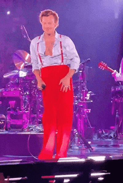 Man In Red Pants And Suspenders Standing On Stage GIF