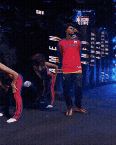 Man In Red Pistons Jersey In Front Of Rising Stars Sign GIF