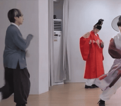 Man In Red Robe Standing Next To Woman In Blue Sweater GIF