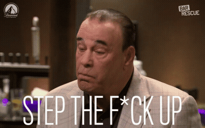 Man In Red Shirt And Black Vest Standing In Dark Room GIF
