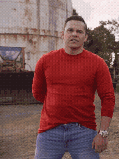 Man In Red Shirt And Blue Jeans In Front Of Rusty Silo GIF