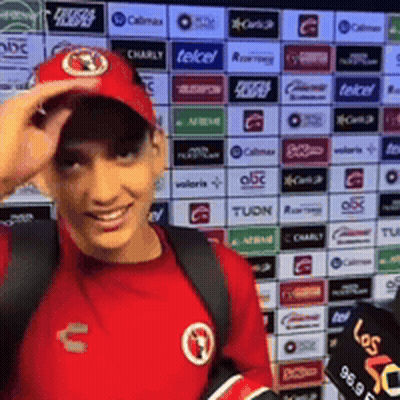 Man In Red Shirt And Hat In Front Of Telcel Ads GIF