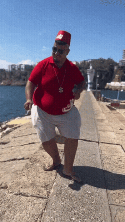 Man In Red Shirt And White Shorts With S Necklace GIF