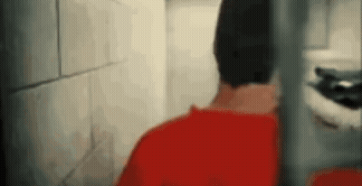 Man In Red Shirt Behind Fence GIF