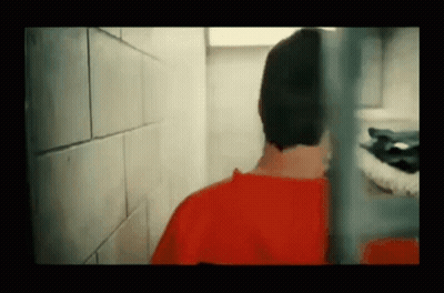 Man In Red Shirt Behind Prison Cell Fence GIF