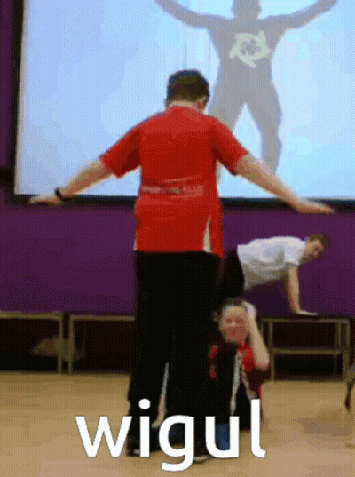 Man In Red Shirt Doing Handstand In Front Of Screen Saying Wigui GIF