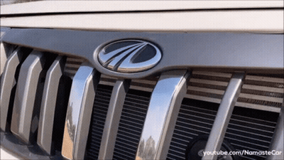 Man In Red Shirt Driving Car With Mahindra Logo GIF