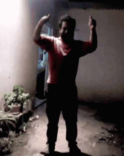 Man In Red Shirt Flexing Muscles In Dark Room GIF