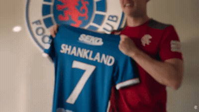 Man In Red Shirt Holding Blue Shankland Shirt GIF