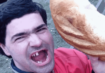 Man In Red Shirt Holding Loaf Over Head GIF