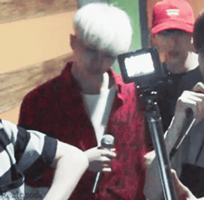 Man In Red Shirt Holding Microphone In Front Of Camera GIF