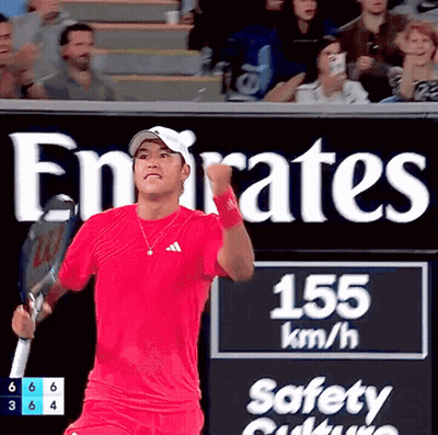 Man In Red Shirt Holding Tennis Racquet In Front Of Emirates Sign GIF