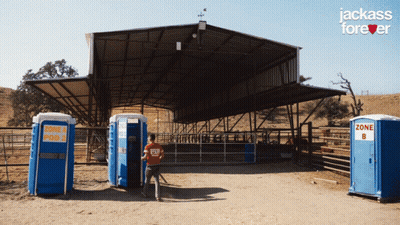 Man In Red Shirt In Front Of Blue Portable Toilets Saying Zone 4 And Pod 2 GIF