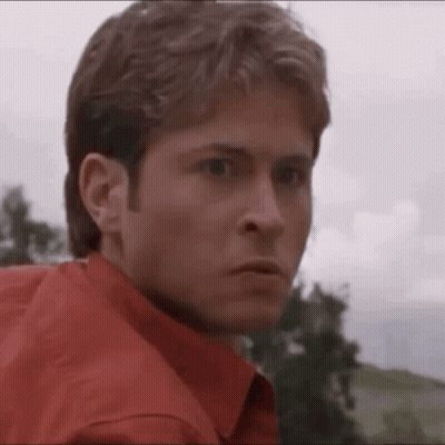 Man In Red Shirt Looking At Camera With Trees GIF
