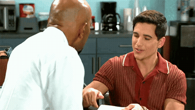 Man In Red Shirt Pointing And Talking To Man In White Shirt GIF