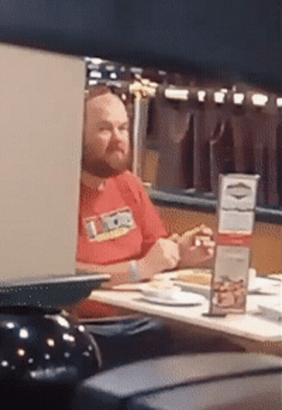 Man In Red Shirt Saying Ice Sitting At Table GIF