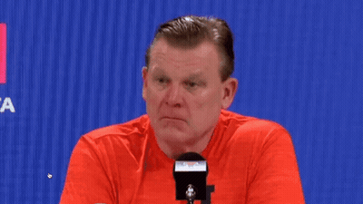 Man In Red Shirt Sitting At Microphone Looking At Camera GIF