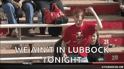 Man In Red Shirt Sitting On Bleacher Saying We Ain't In Lubbock Tonight GIF