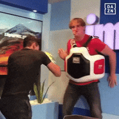 Man In Red Shirt Standing In Front Of Da Zn Sign GIF